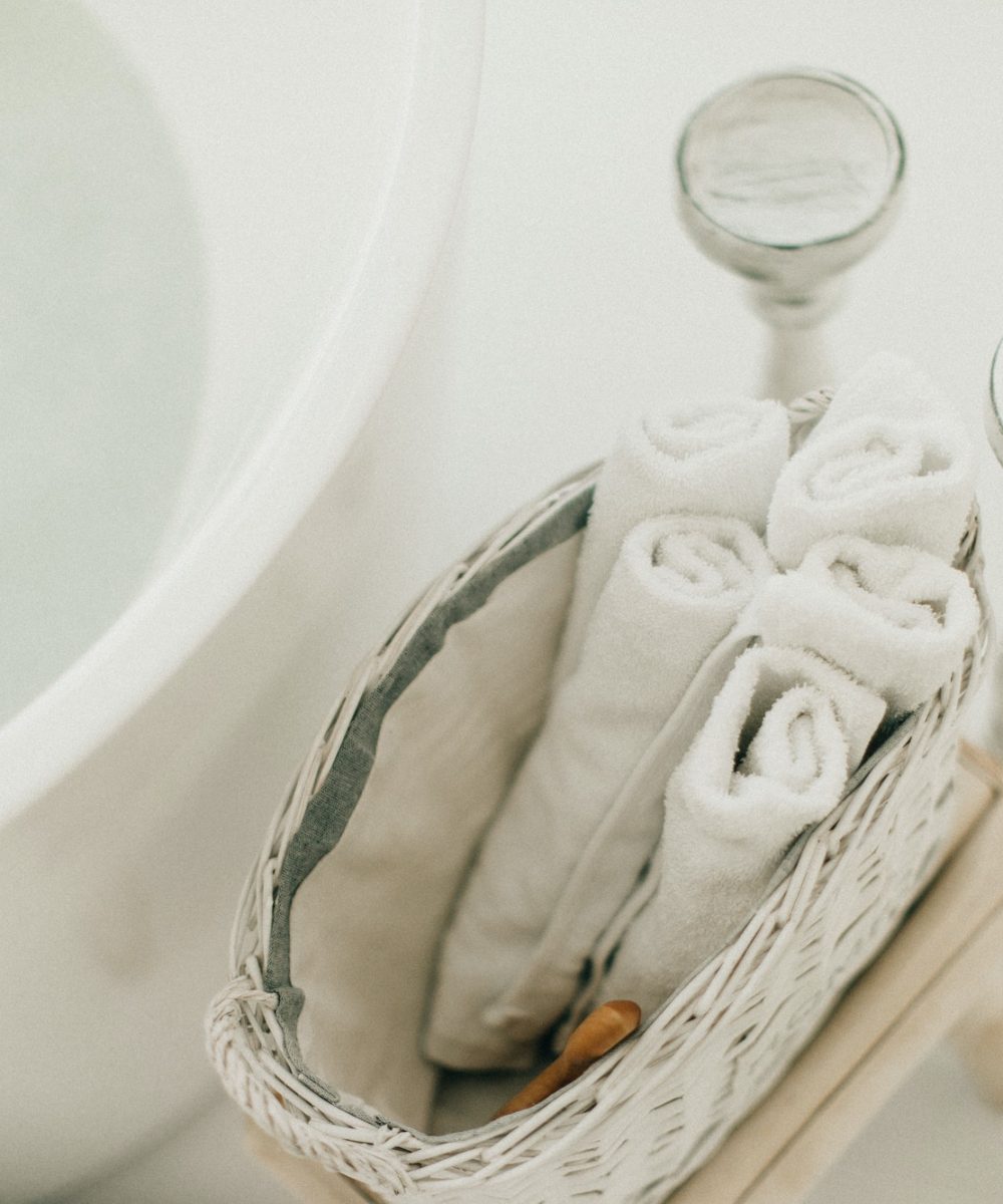 white bath towels are in a basket in the bathroom